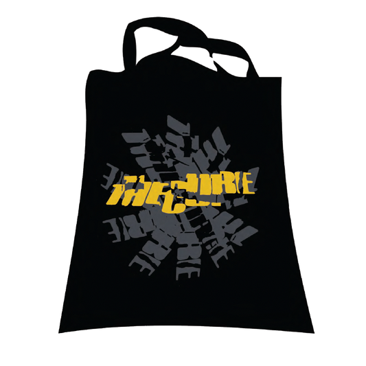 Black tote bag with cracked "The Cure" logo in yellow printed over a grey stamped logo design.